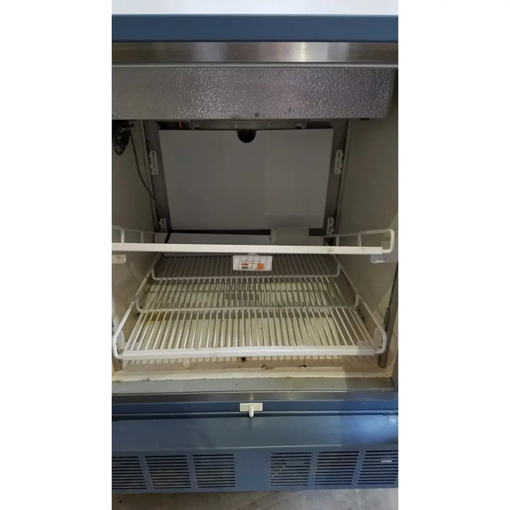 The interior of a stainless steel helmer hlf105 horizon series laboratory freezer with white wire shelves and blue exterior