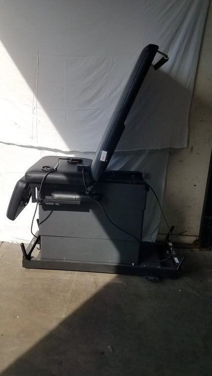 Black padded reclining physical therapy treatment table with adjustable headrest and footrest on metal base for mobilization