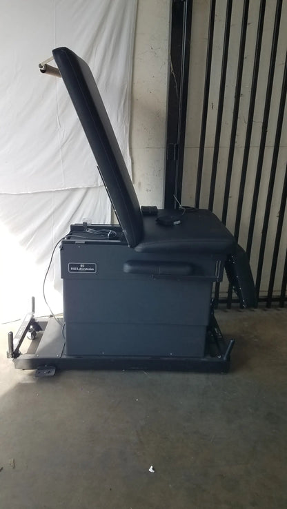 Black leather physical therapy treatment chair with reclining feature, adjustable headrest, footrest, and metal frame
