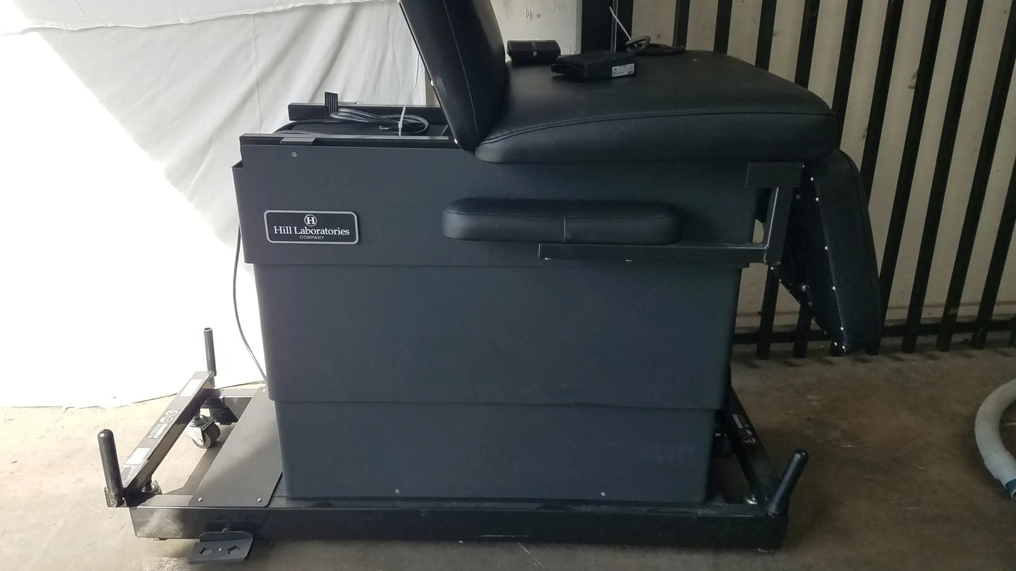 Black leather reclining physical therapy treatment table with sturdy metal frame and wheels by hill laboratories