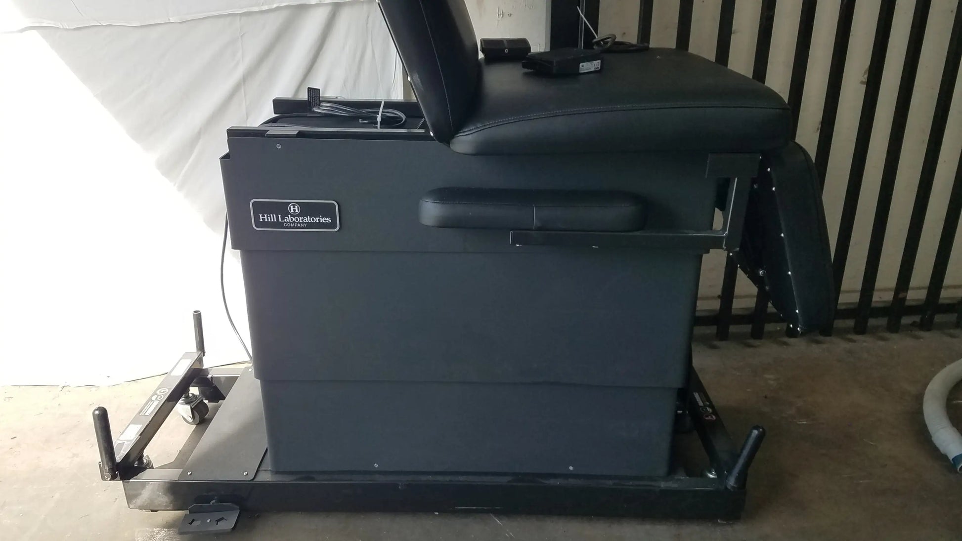 Black leather reclining physical therapy treatment table with sturdy metal frame and wheels by hill laboratories