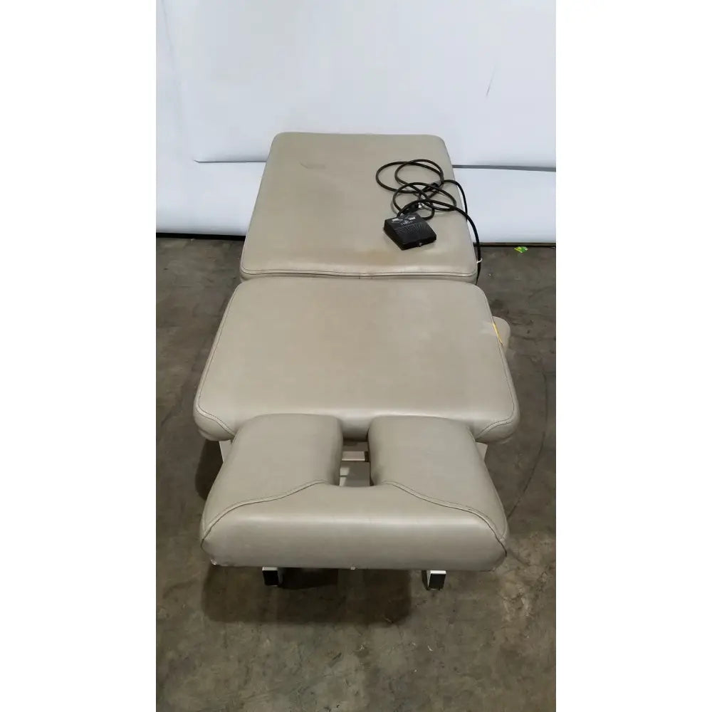 Beige leather hill model ha90pt physical therapy treatment table with adjustable sections and black foot pedal on surface
