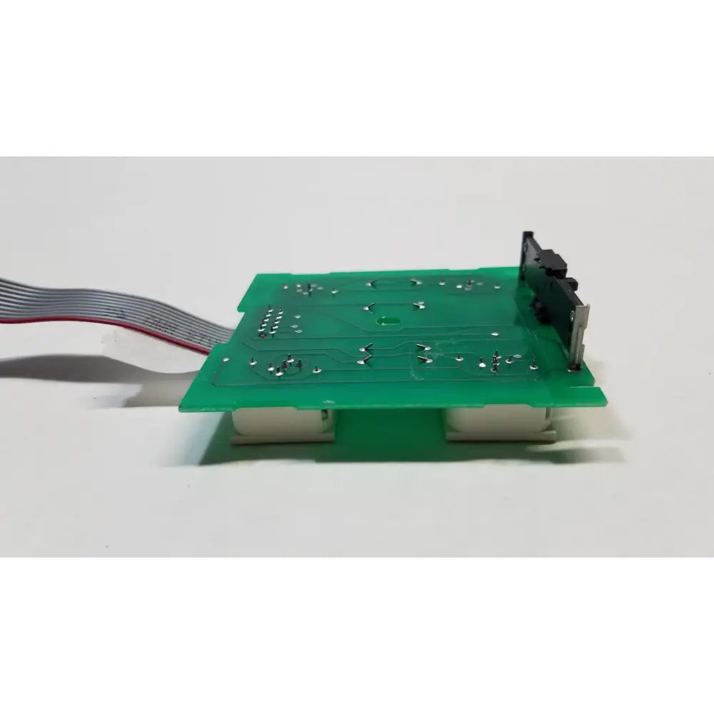 Green rectangular hill rom total care switch board with silver solder points and gray ribbon cable attached