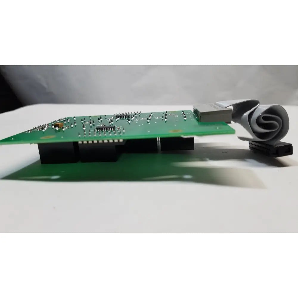 Green printed circuit board with electronic components and gray ribbon cable for hill rom total care ent light relay control board assy