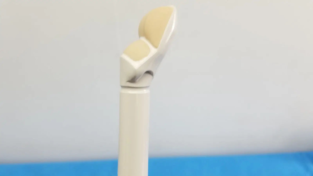 A beige and silver prosthetic knee joint with smooth curves shown alongside the hitachi cc41r ultrasound probe 8 4 mhz