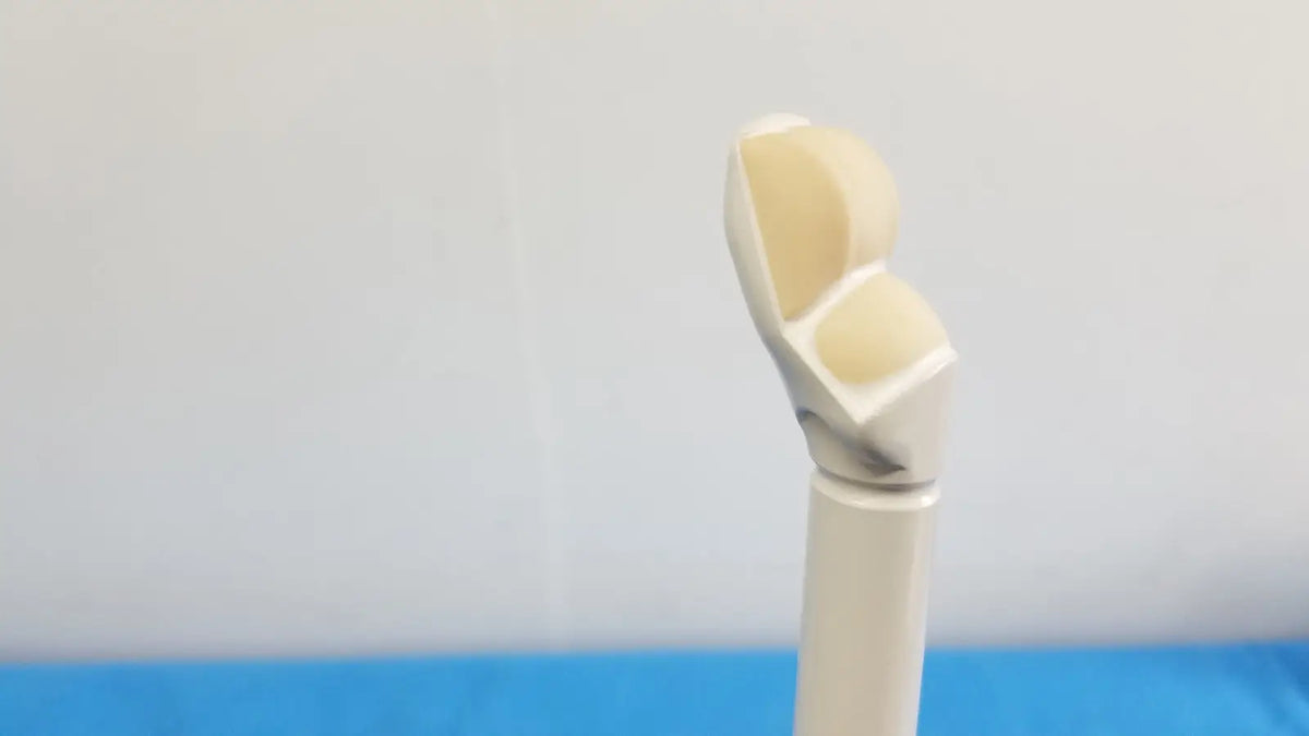 A beige and white smooth curved prosthetic finger alongside the hitachi cc41r ultrasound probe 8-4 mhz device