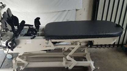 White hocoma erigo pro robotic tilt table with black padded surface and adjustable armrests for verticalization therapy