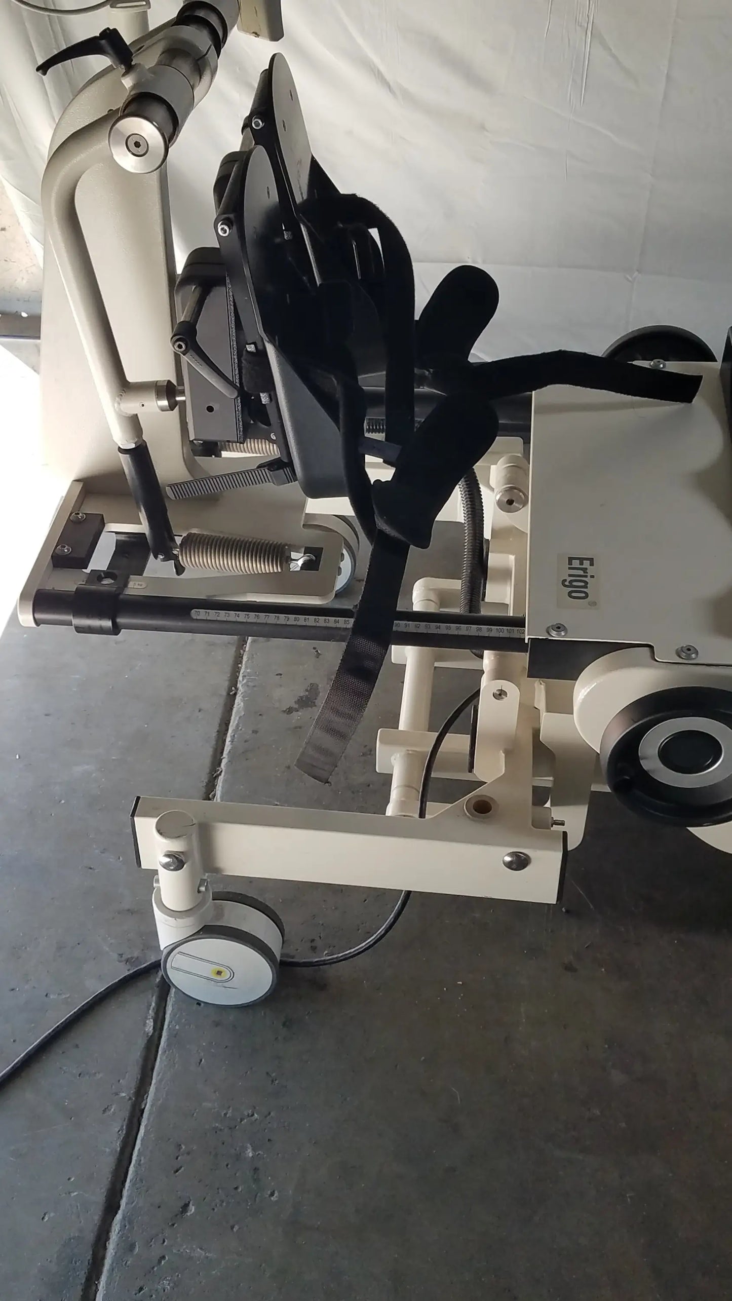 White medical robotic tilt table with black straps and wheels for verticalization therapy hocoma erigo pro system