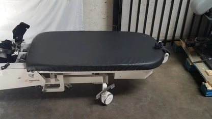 Black padded surface on white hologic robotic tilt table with adjustable features and caster wheels for verticalization therapy