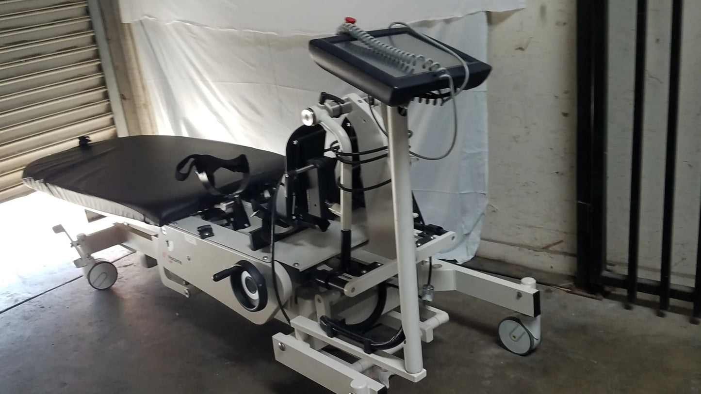 White medical rehabilitation robotic tilt table with black padded surface and adjustable armrests for verticalization therapy