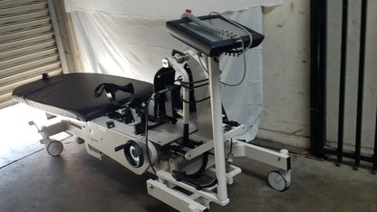 White medical rehabilitation robotic tilt table with black padded surface and adjustable armrests for verticalization therapy
