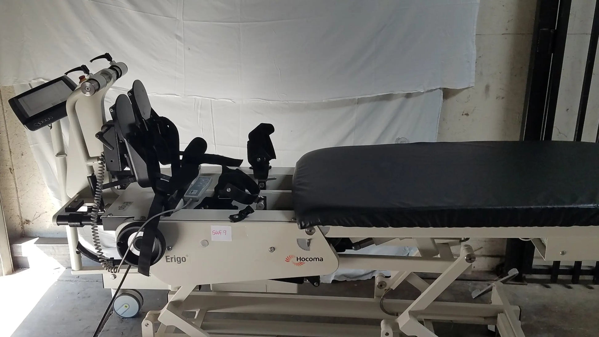 White and black hocoma erigo pro robotic tilt table with adjustable padded bed and control screen for verticalization therapy