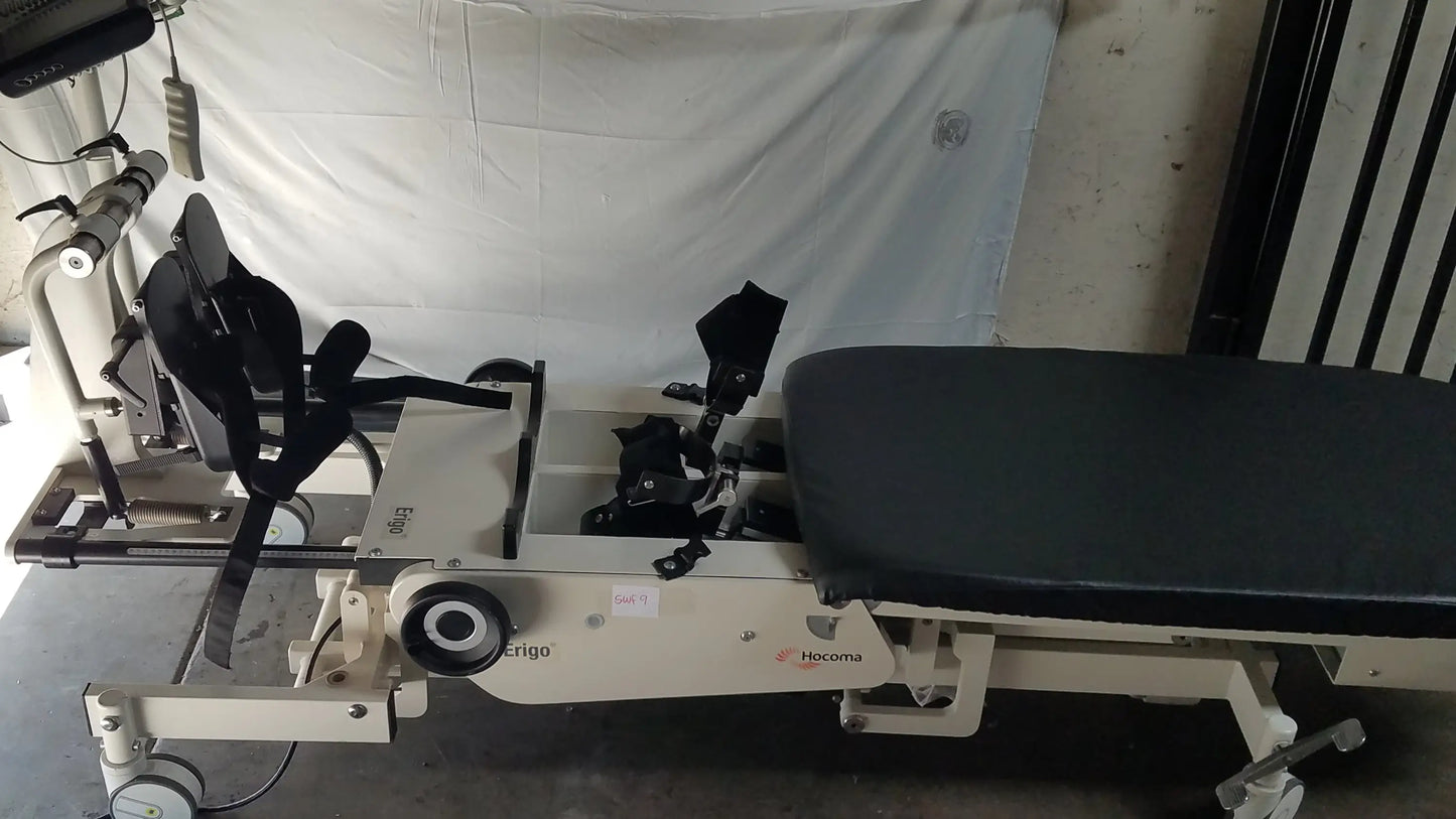 Beige hocoma erigo pro robotic tilt table with black padded seat and adjustable leg supports for verticalization therapy