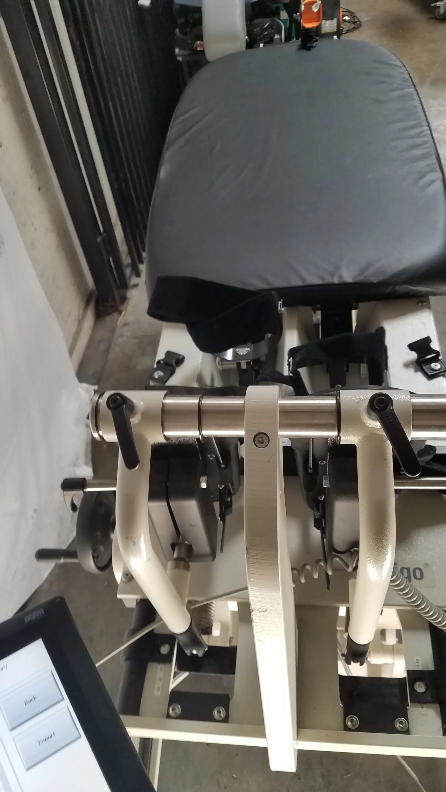 Gray padded robotic tilt table with metallic frame and black adjustment levers for Hocoma Erigo Pro therapy system