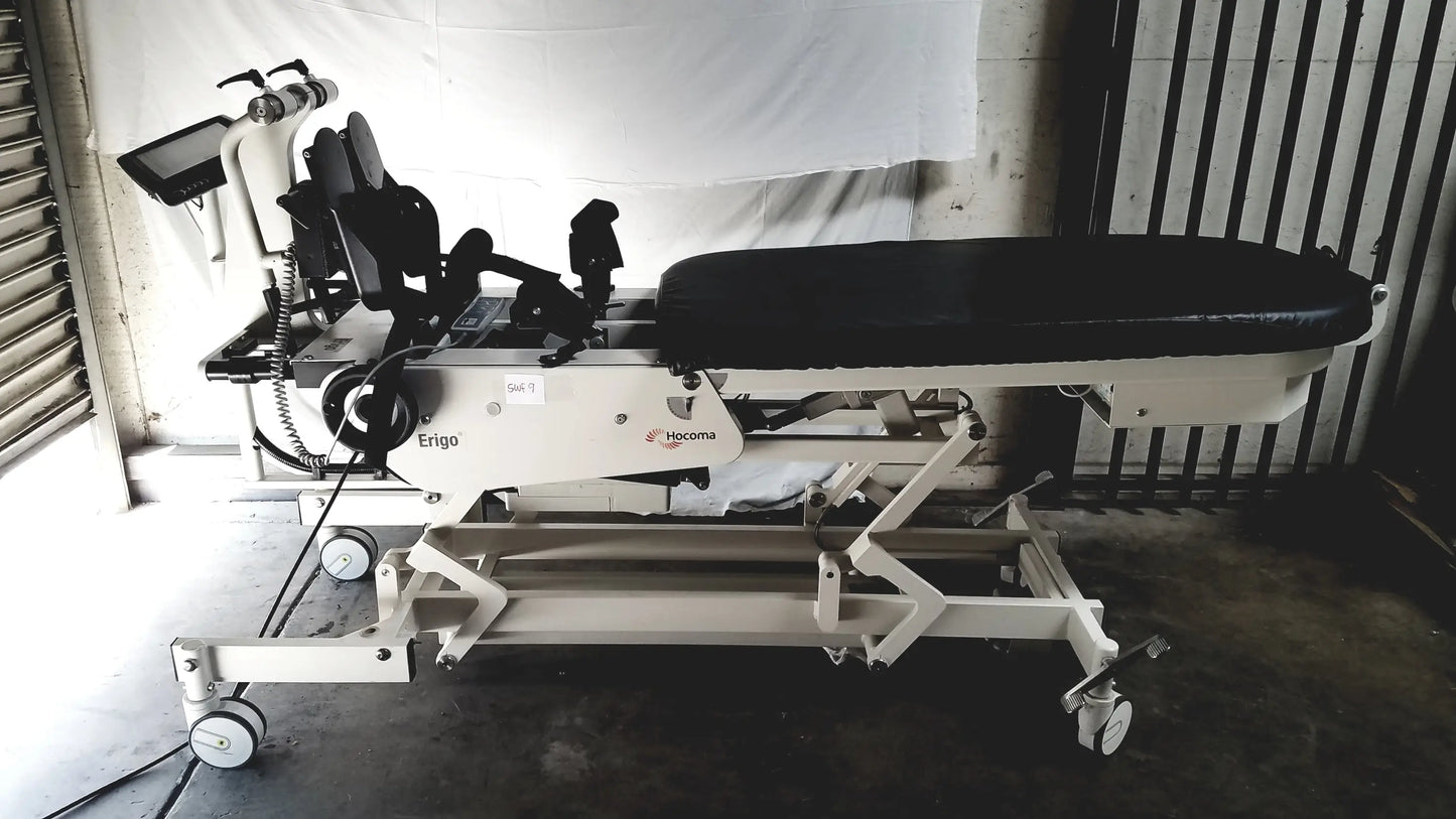 White medical robotic tilt table with black padded surface and adjustable armrests featuring ergo branding