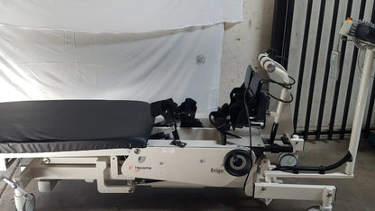 White hocoma erigo pro robotic tilt table with black padded surface and adjustable mechanical arms for verticalization therapy