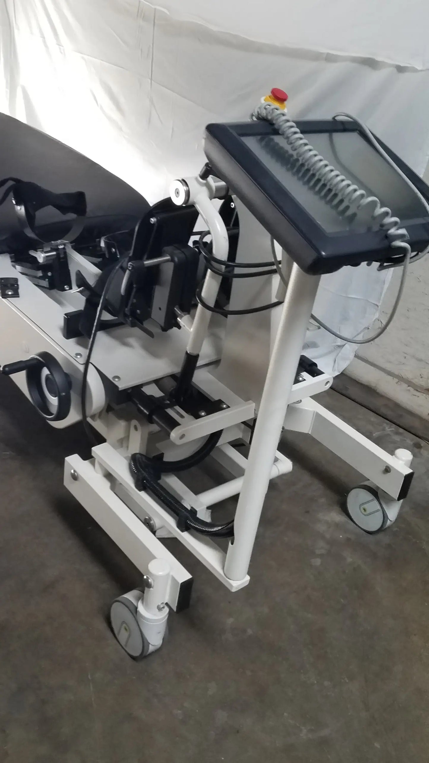 White medical-grade robotic tilt table with black touchscreen console and adjustable patient support system by hocoma erigo pro