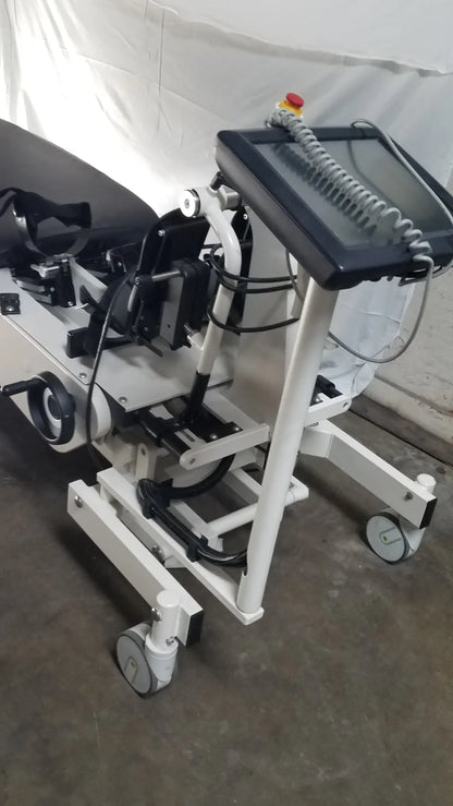 White medical-grade robotic tilt table with black touchscreen console and adjustable patient support system by hocoma erigo pro