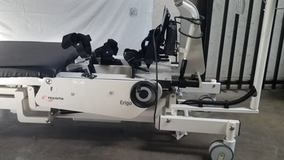 White hocoma erigo pro robotic tilt table with black padded sections and adjustable armrests for rehabilitation therapy
