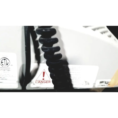 Black coiled cord attached to the back of a white howard medical hi-care medical hi-care monitor and stand appliance