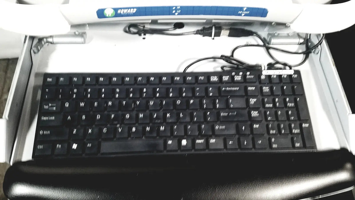 Black keyboard with white lettering and black wrist rest beneath in howard medical hi-care monitor and stand product setup