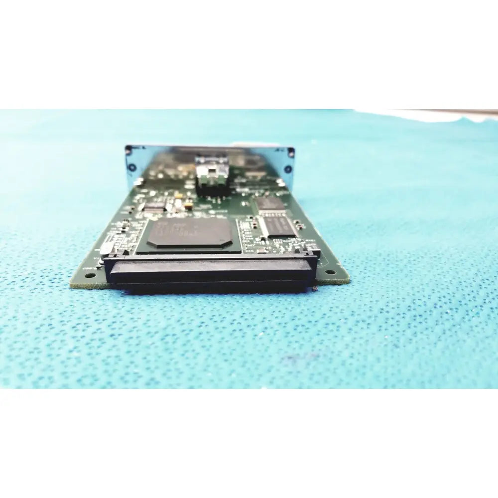 Green circuit board with black components and silver metal bracket of hp jetdirect 620n fast ethernet print server