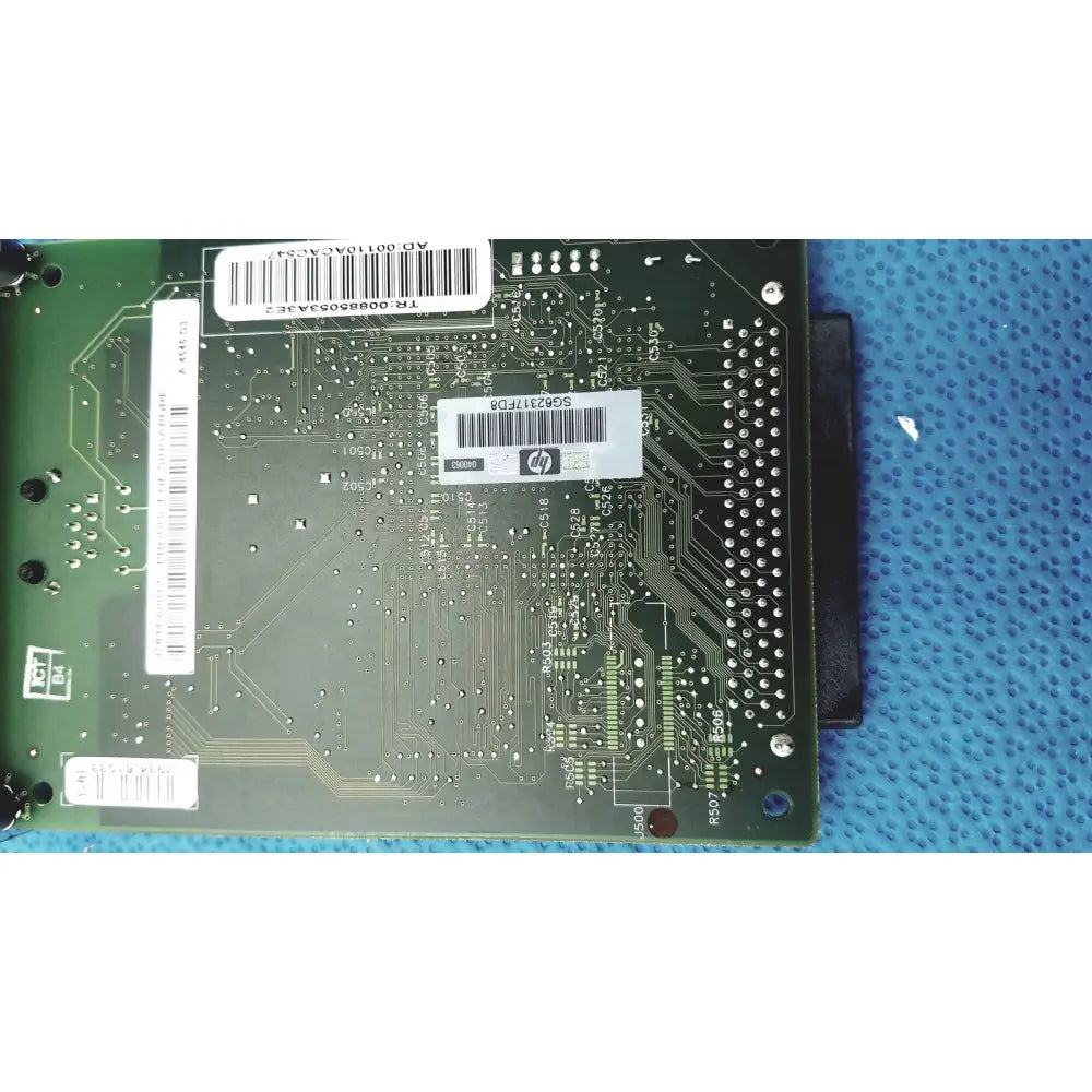 Green hp jetdirect 620n circuit board with white barcode labels and metallic solder points for fast ethernet print server