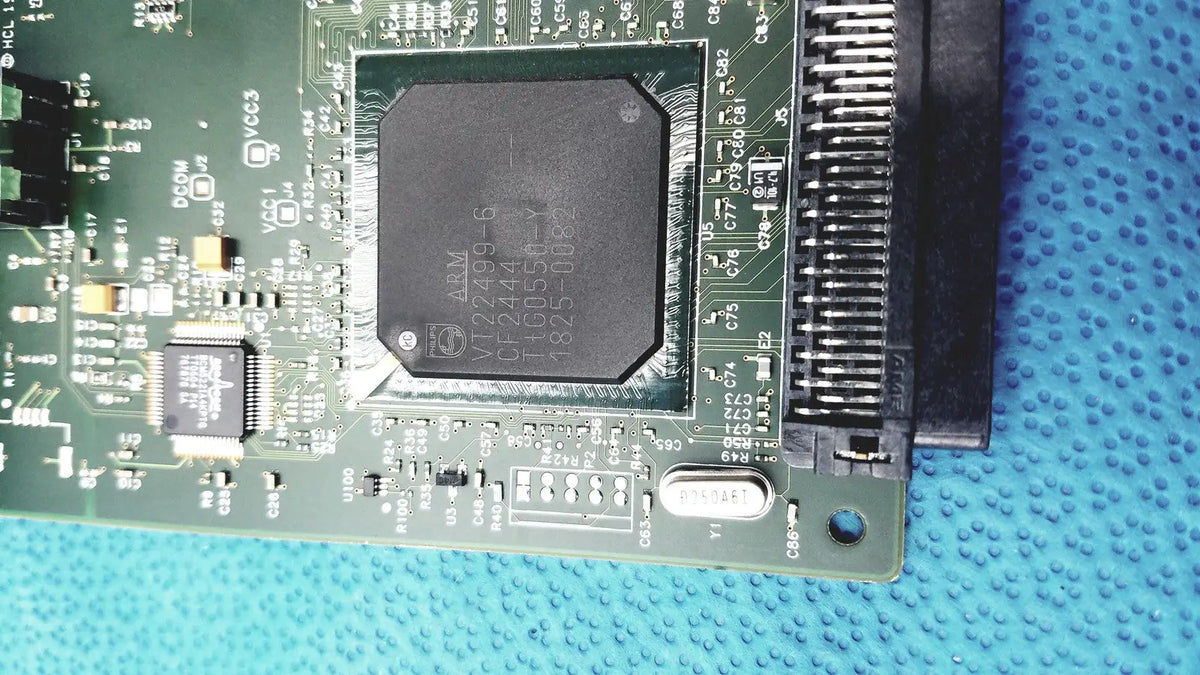 Black rectangular integrated circuit chip mounted on green pcb of hp jetdirect 620n fast ethernet print server