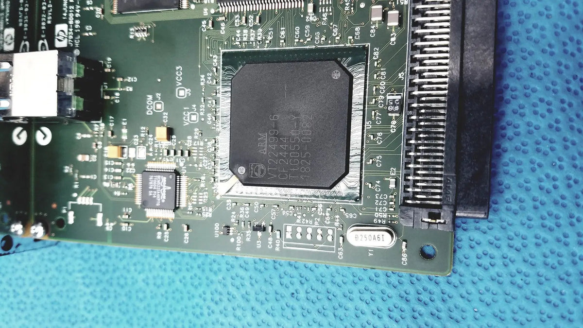 Black rectangular integrated circuit chip on green pcb of hp jetdirect 620n fast ethernet print server board