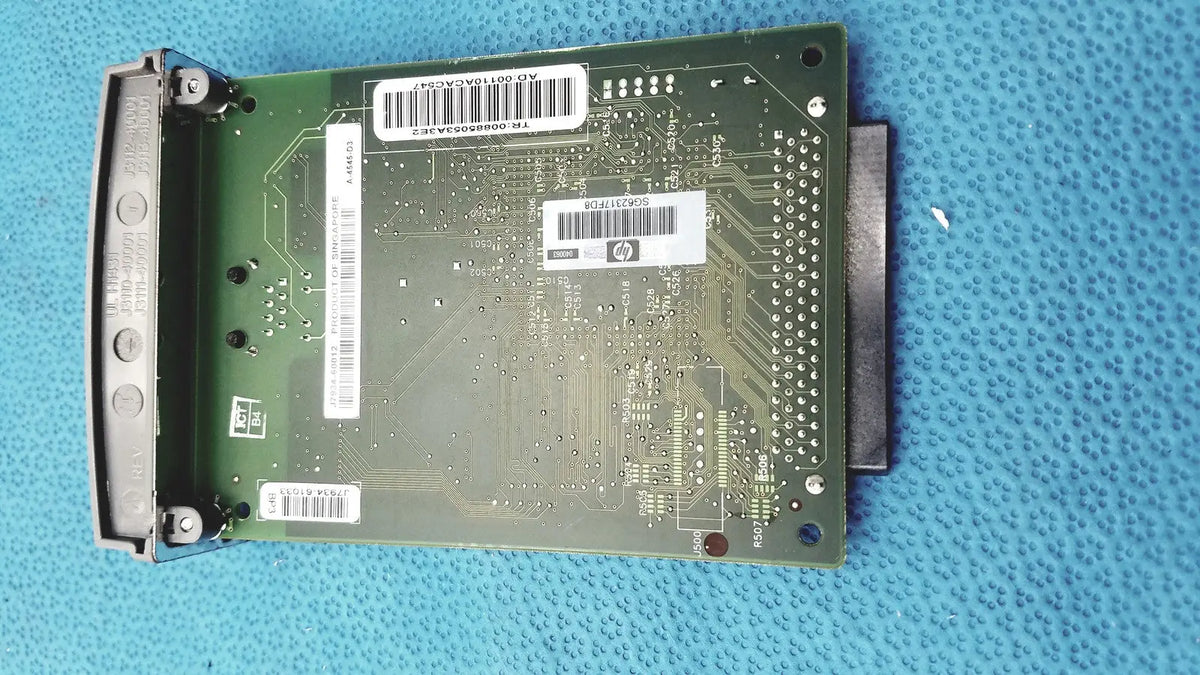 Green circuit board with silver connectors and white barcode labels of hp jetdirect 620n fast ethernet print server