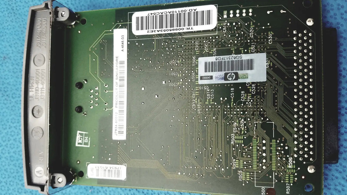 Green hp jetdirect 620n circuit board with silver solder points and white barcode labels for fast ethernet print server