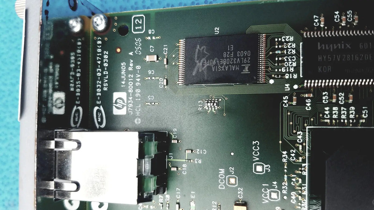 Green circuit board with black integrated circuits and silver connectors in hp jetdirect 620n fast ethernet print server
