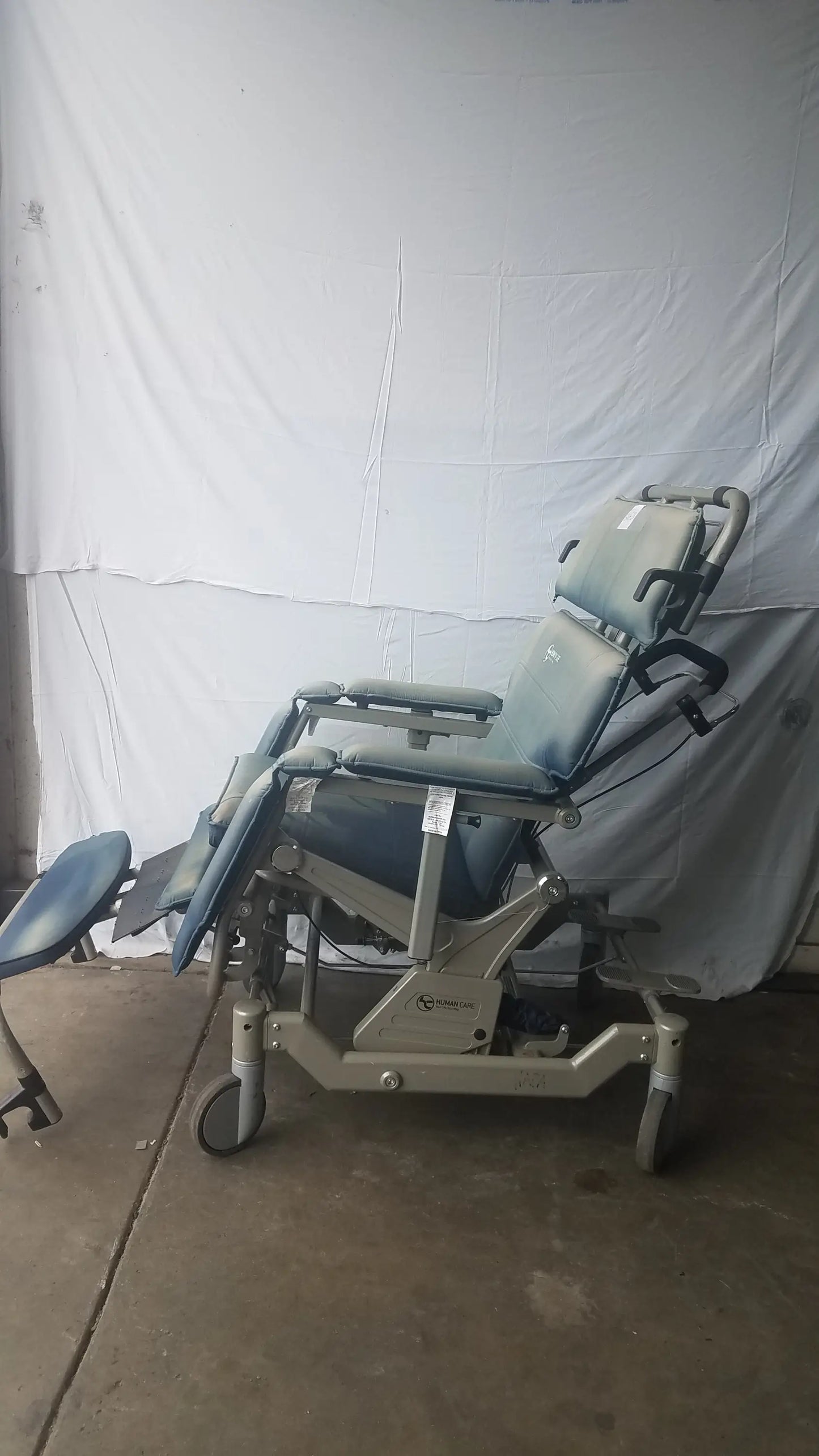 Gray adjustable humanCare I-400 bariatric convertible chair with padded upholstery and wheeled base for medical exams