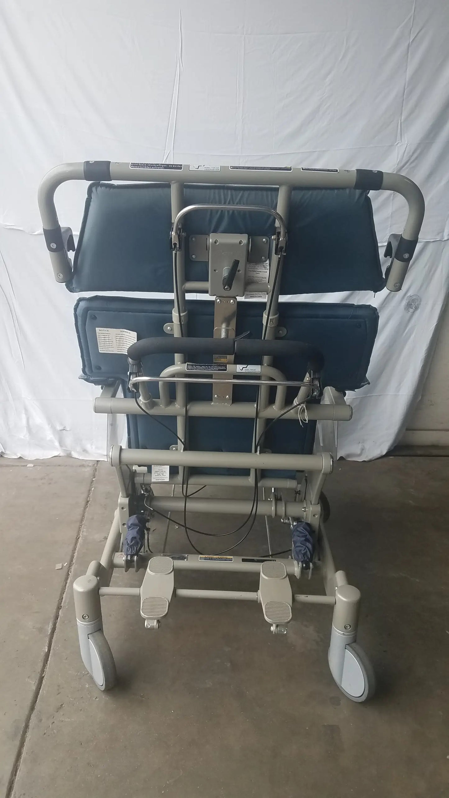 HumanCare I-400 bariatric convertible chair with gray metal frame, blue padded seat, adjustable foot pedals, and caster wheels