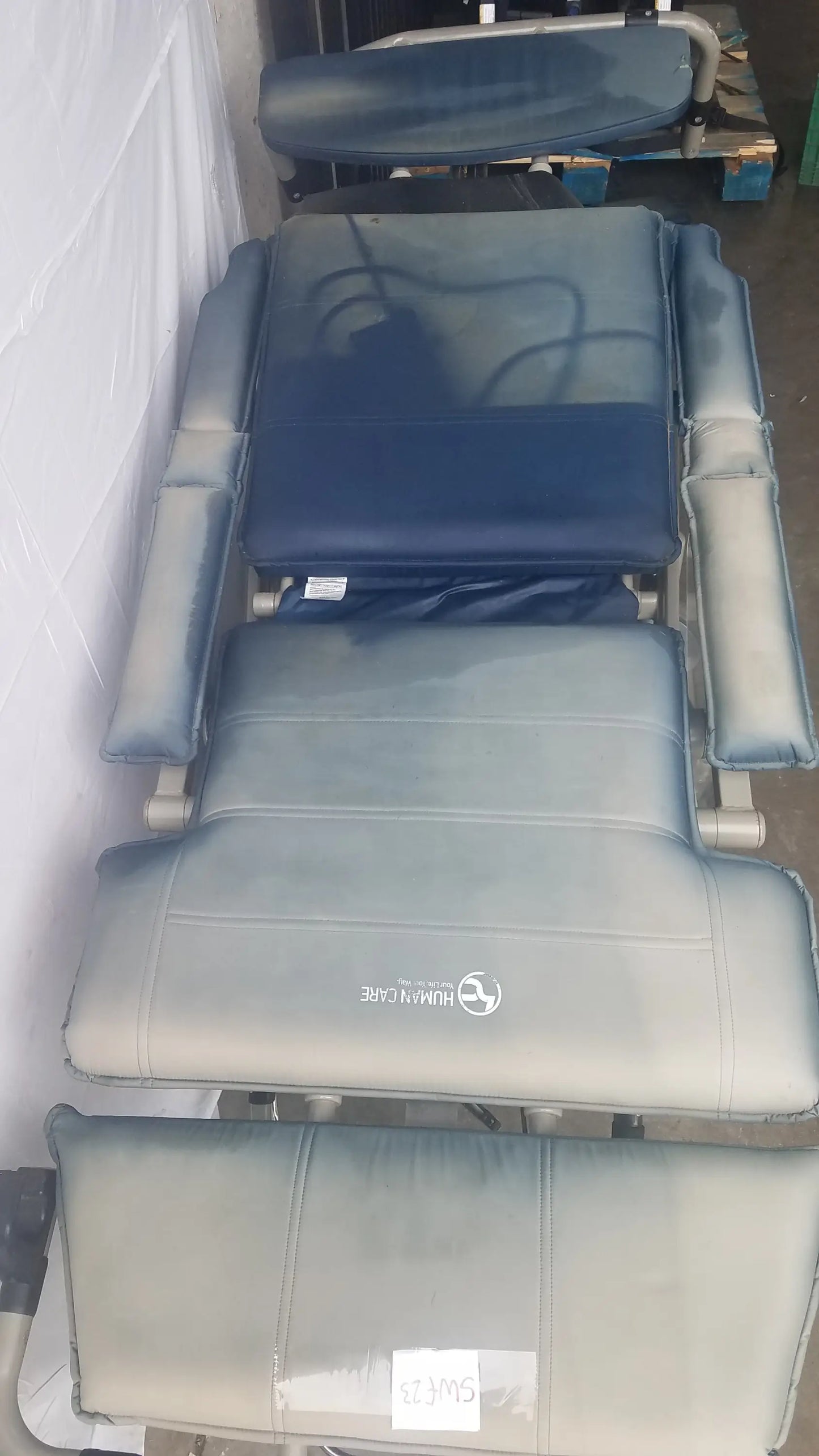 Gray upholstered bariatric convertible chair with adjustable sections and human care logo on the headrest