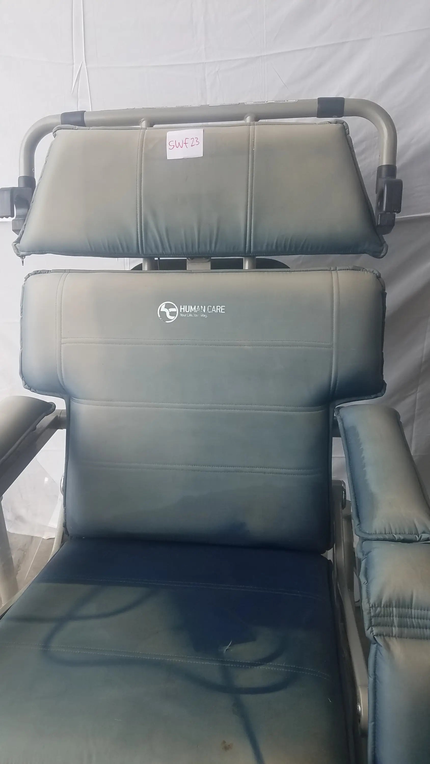 Gray upholstered bariatric convertible chair with metal frame showing human care logo on backrest rear view
