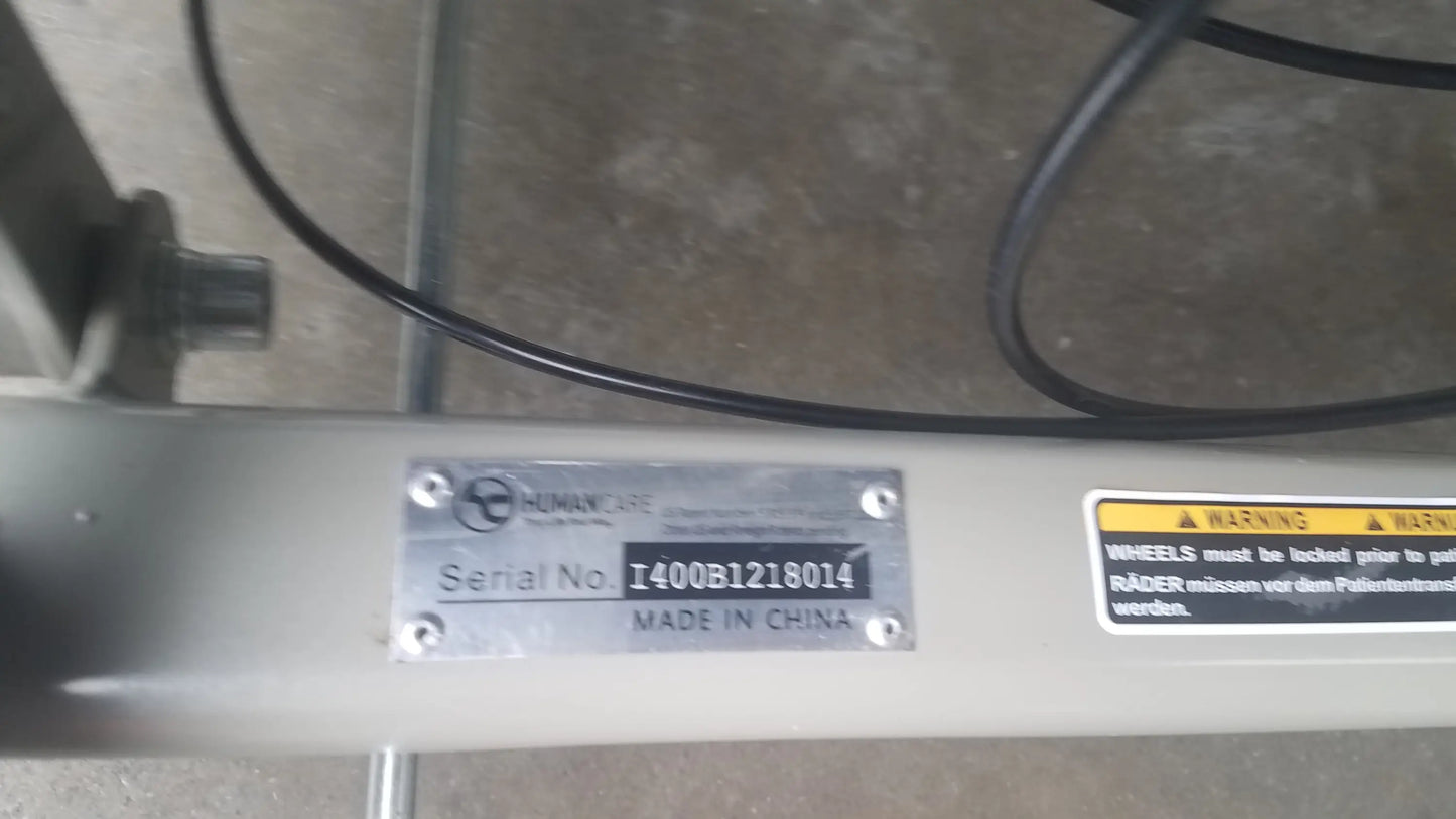 Silver metal plate on the back of humancare i-400 bariatric convertible chair with serial number and warning label