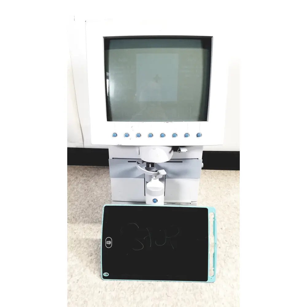 White humphery instruments 350 lens analyzer with monitor and mechanical arm positioned above black chalkboard with blue edges