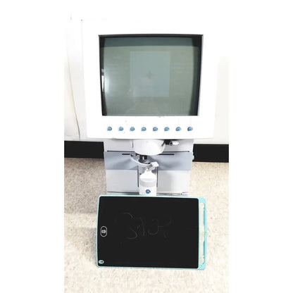 White humphery instruments 350 lens analyzer with monitor and mechanical arm positioned above black chalkboard with blue edges