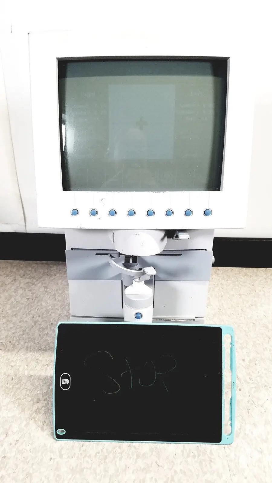 White humphery instruments 350 lens analyzer with monitor and mechanical arm positioned above black chalkboard with blue edges