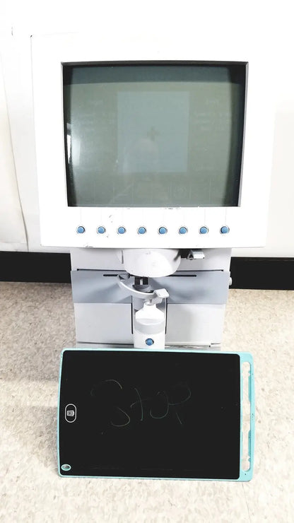 White humphery instruments 350 lens analyzer with monitor and mechanical arm positioned above black chalkboard with blue edges