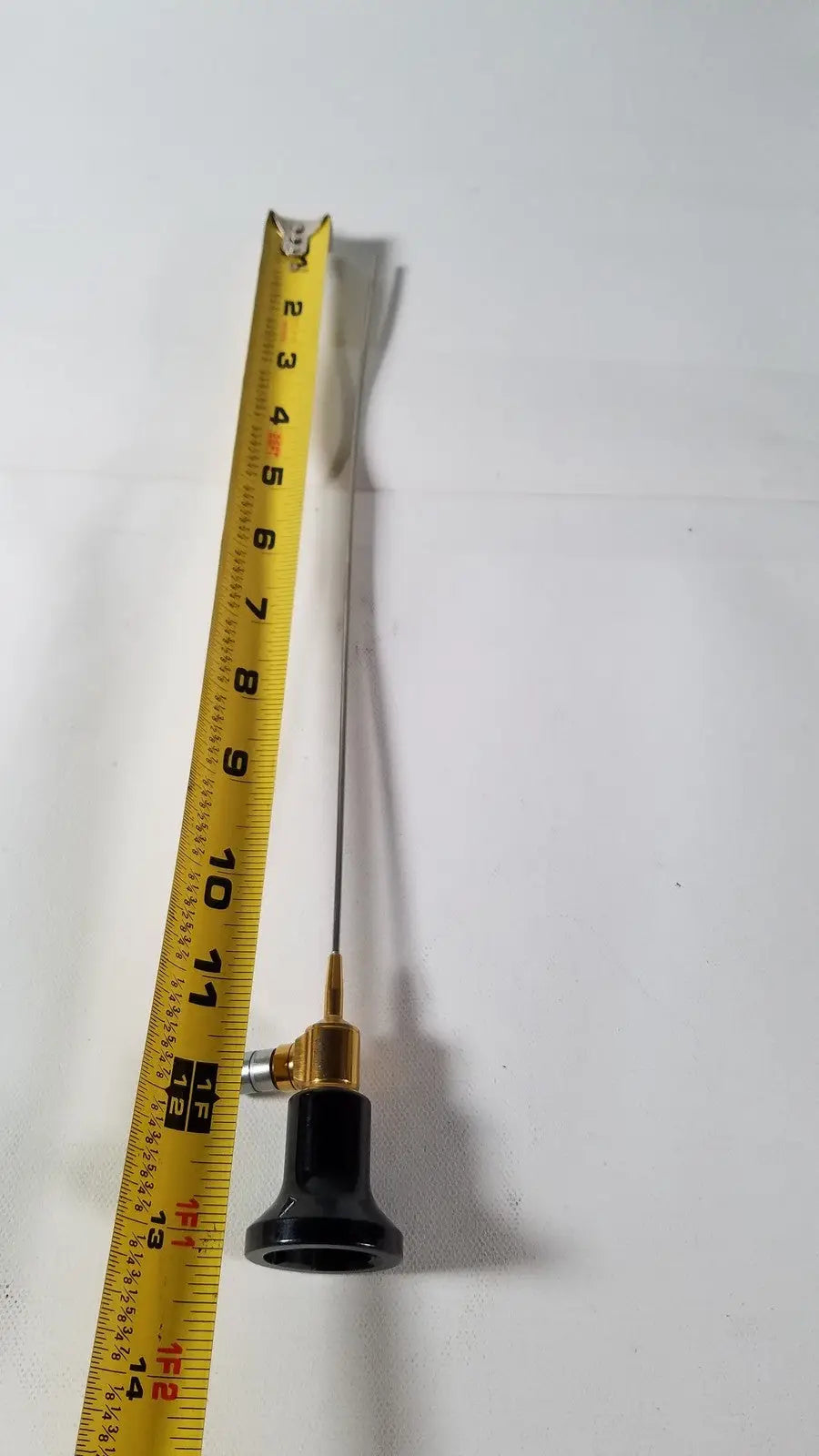 A slender metallic imagyn microlap ml-gold cystoscope with black handle and gold-colored joint for precision use