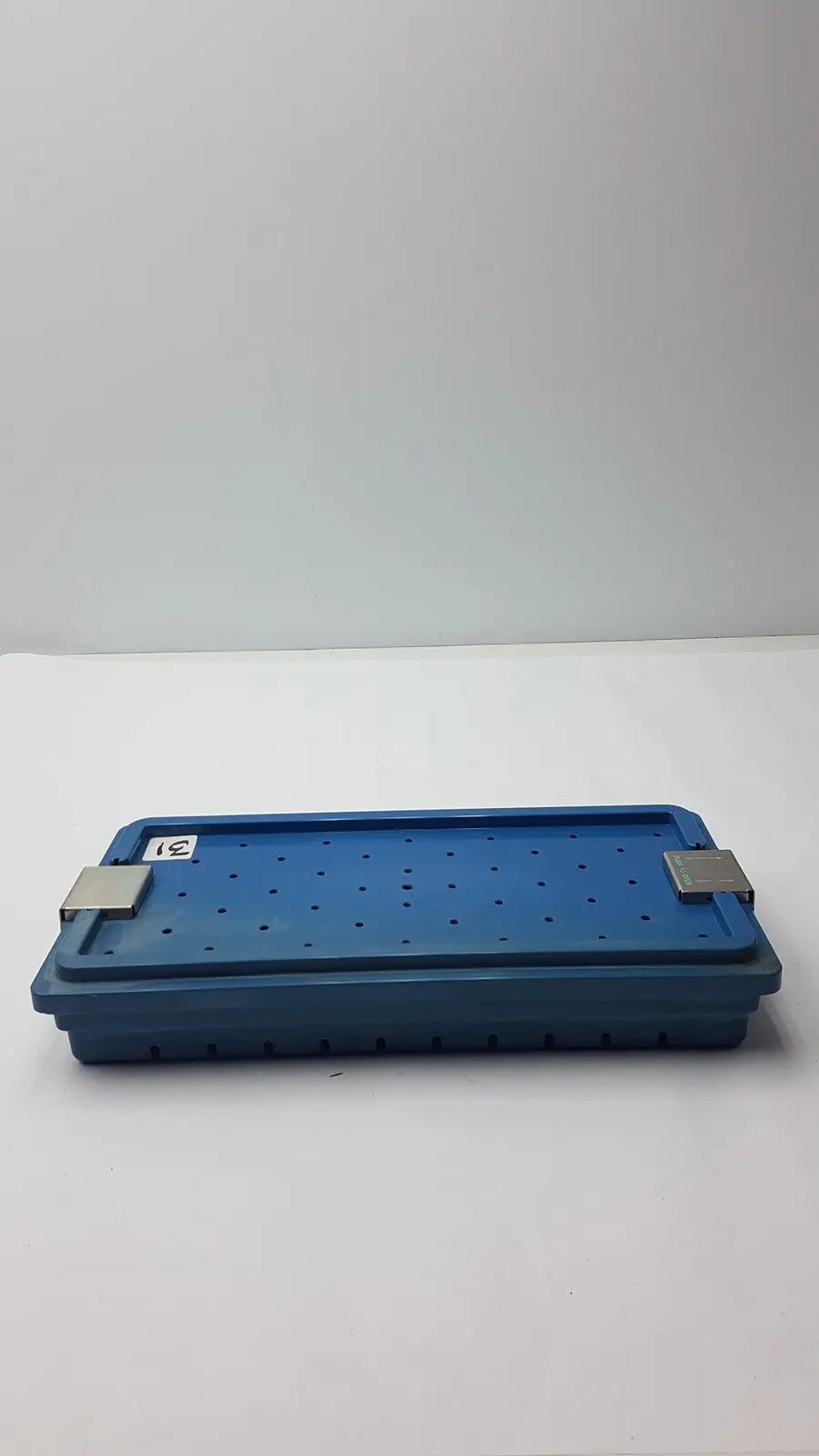 Blue plastic instrument set case container with silver metal latches and perforated surface for case container sterilization