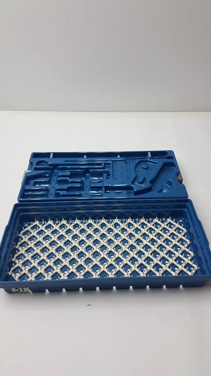 Blue plastic instrument set case with white grid-patterned interior for sterilization and storage container