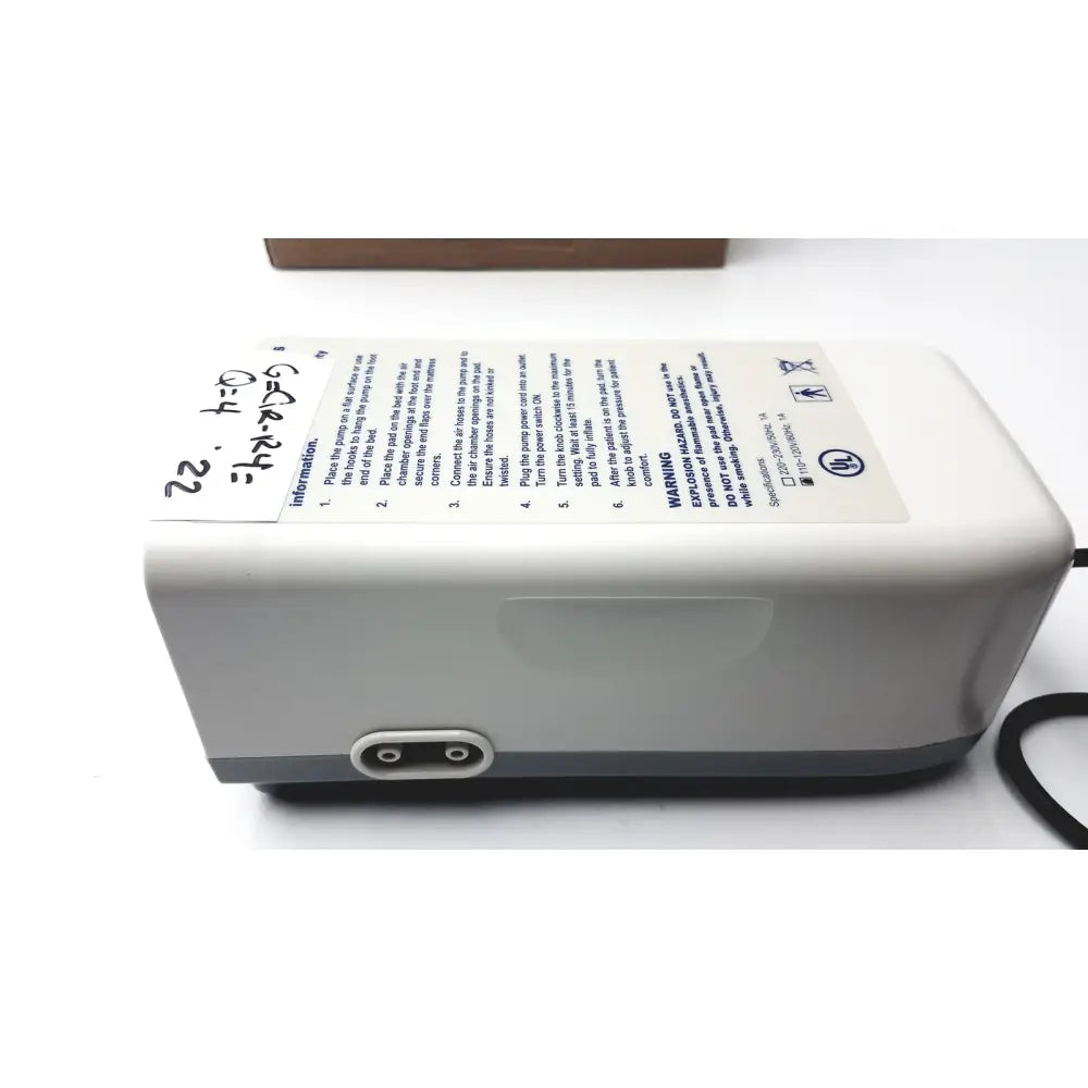 Gray plastic invacare alternating pressure pump cg9701 with black power cord and white instruction label shown from the back side