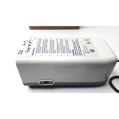 Gray plastic invacare alternating pressure pump cg9701 with black power cord and white instruction label shown from the back side