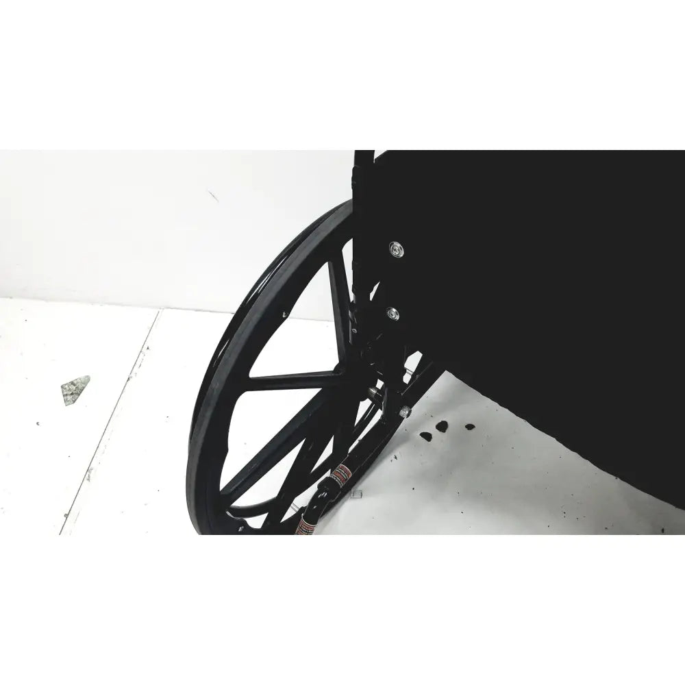 Black wheelchair wheel with metallic spokes and dark frame shown from the back of invacare tracer sx5 manual folding wheelchair