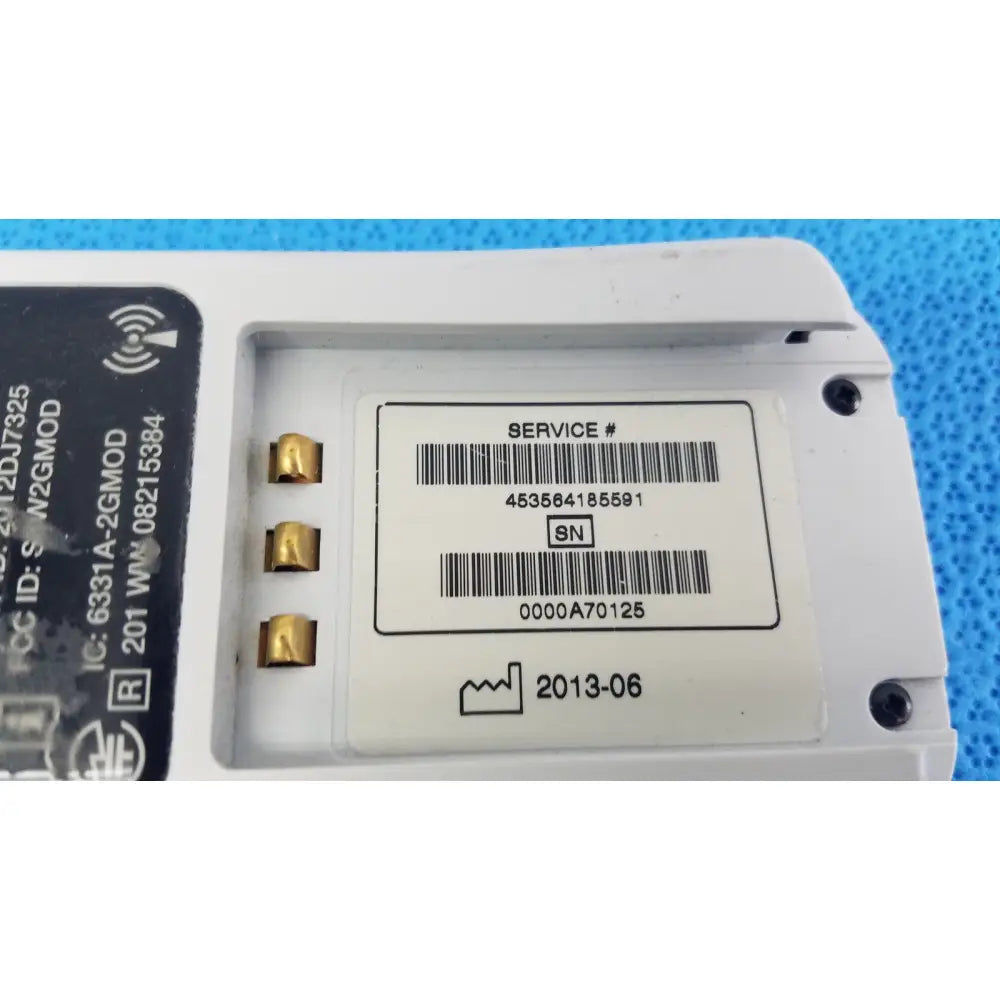 White plastic battery with gold terminals and black label showing service numbers on invivo medical wireless ecg module back side
