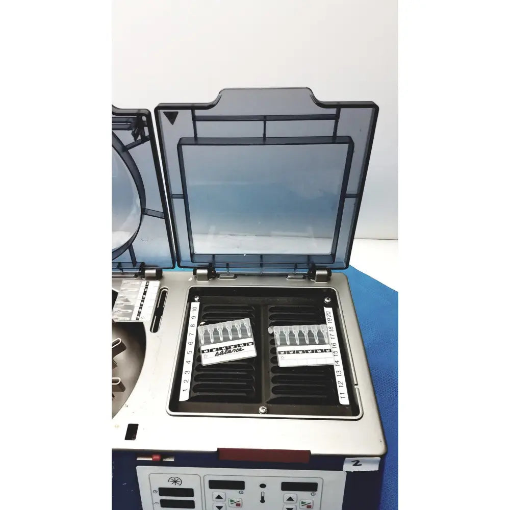 Silver and black laboratory centrifuge with transparent lid and numbered slots in j&j ortho-clinical diagnostic ivd ortho workstation unit