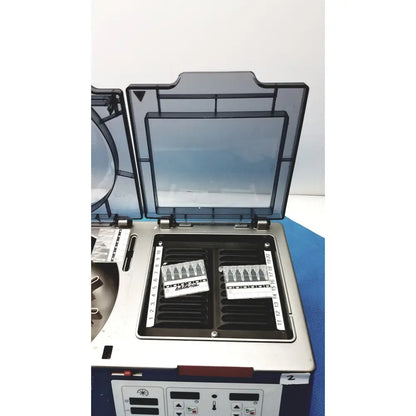 Silver and black laboratory centrifuge with transparent lid and numbered slots in j&j ortho-clinical diagnostic ivd ortho workstation unit